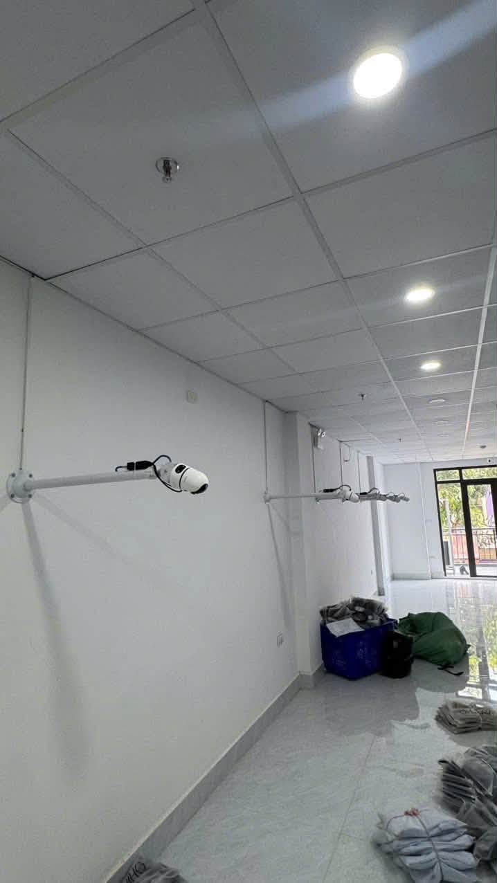 Camera đóng hàng lắp trên tay treo gắn tường trong xưởng may kiêm kho, nhìn dọc lối đi có các bó hàng xếp dưới sàn
